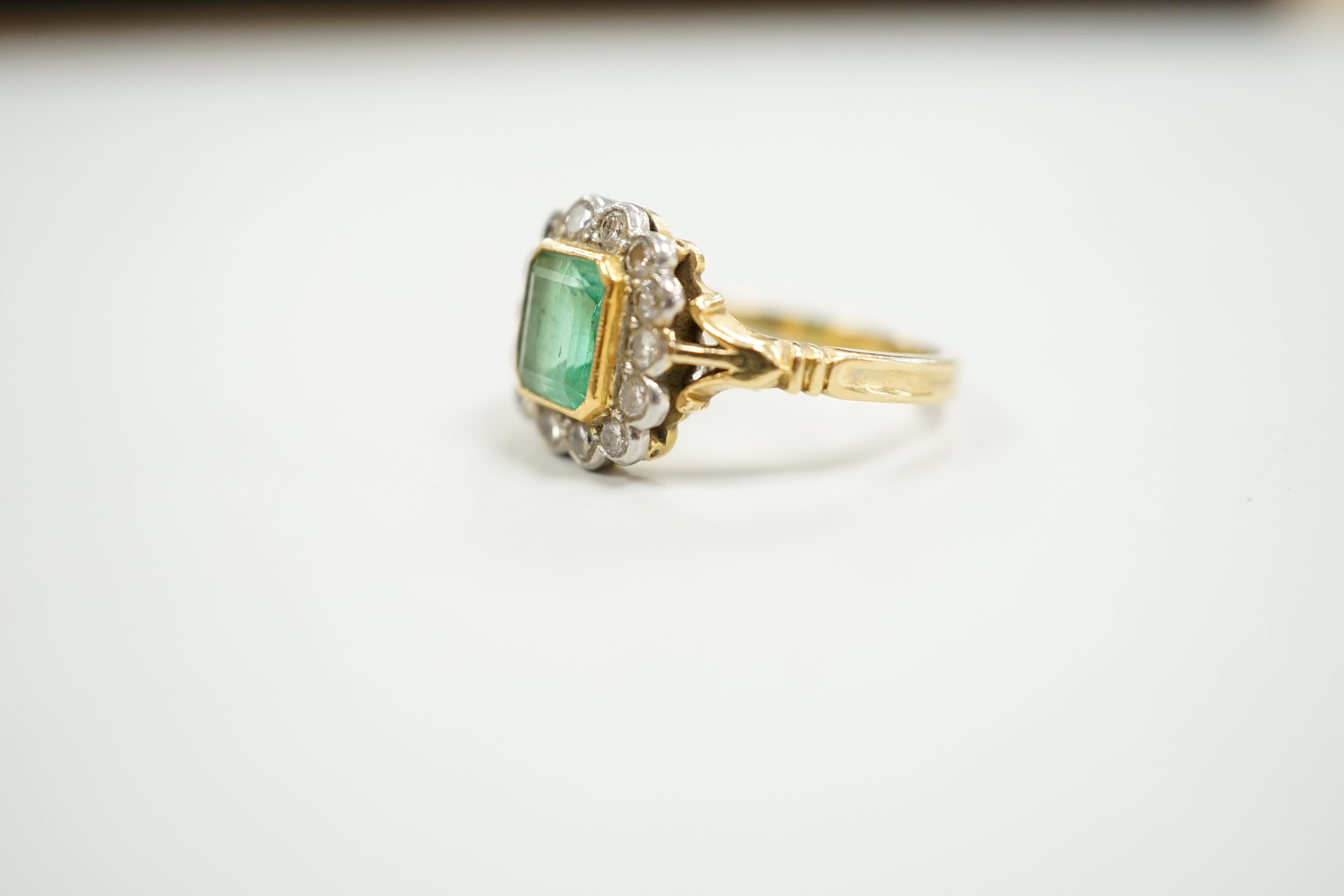 A modern 18ct gold, emerald and diamond set circular cluster ring, size O, gross weight 5 grams.